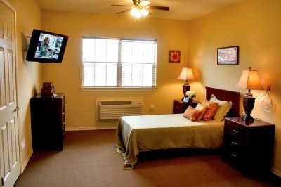Bedroom with small bed, windows and a TV
