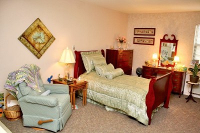 Bedroom with small bed, reclining chair and dresser
