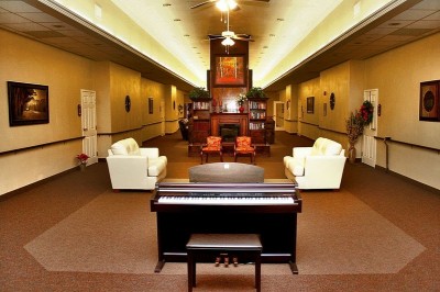 Long common area with black piano and two white couches