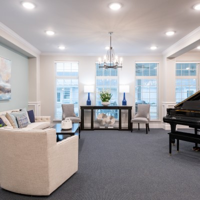 large white room with modern decor, seating area and grand piano